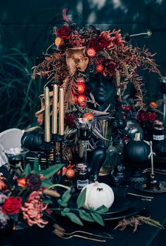 a table topped with black plates covered in halloween decorations and candles, surrounded by pumpkins