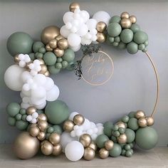 a wreath made out of balloons and greenery is displayed in front of a wall