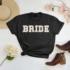 a t - shirt with the word bride on it next to some shoes and flowers