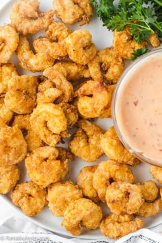 a white plate topped with fried tater tots next to a bowl of dipping sauce