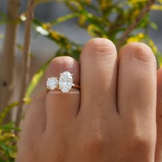 a person's hand with two diamond rings on their fingers and one is holding the other