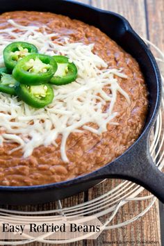 an easy refried beans recipe in a skillet with cheese and jalapenos