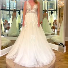 a woman standing in front of a mirror wearing a wedding dress