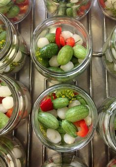 several glass jars filled with pickles and other vegetables on top of a metal surface