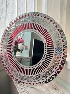 a mirror sitting on top of a wooden table next to a vase with flowers in it