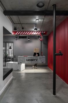 an empty room with red walls and black metal pipes on the floor, along with a sign that reads logity