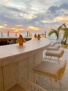 several chairs and tables are lined up on the beach at sunset or sunrise, with palm trees in the background