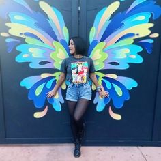 a woman standing in front of a painted butterfly