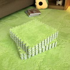 a living room with a green rug on the floor and a book shelf next to it