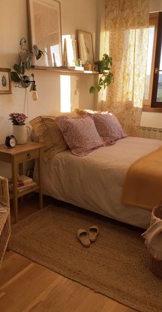 a bed sitting next to a window in a room with wooden flooring and furniture