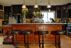 three stools in front of a bar with flowers on it