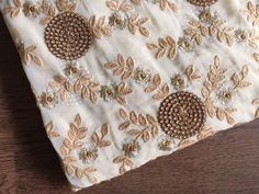 a table cloth with gold and white flowers on it sitting on top of a wooden floor