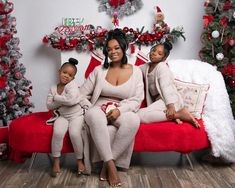 two women sitting on a red couch in front of christmas decorations