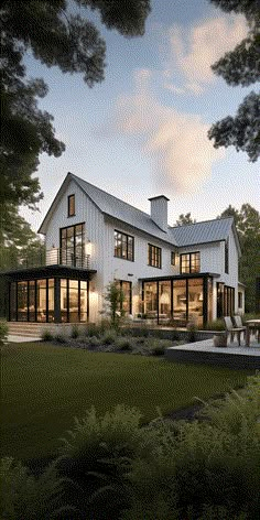 a large white house sitting on top of a lush green field next to a forest