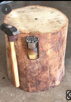 an old tree stump with a hammer and nut in it's center, sitting on concrete