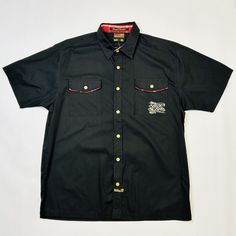 Elevate Your Wardrobe With This Stylish Southpole Hexagon Product Skulls Shirt In Size Xl. The Short Sleeve Button-Up Shirt Features A Black Cotton Fabric With A Graphic Print Of Skulls And A Southpole Logo Embroidered On The Chest. The Collared Neckline And Point Collar Style Make It Perfect For Any Occasion, Whether It's A Travel Adventure, A Party, Or A Casual Day Out. The Shirt Also Has Some Great Features, Including Easy Care, Pockets, And Being Suitable For All Seasons. The Southpole Big L Classic Shirt With Buttons For Streetwear, Classic Streetwear Shirt With Snap Buttons, Black Cotton Camp Shirt With Pockets, Black Cotton Camp Shirt With Buttons, Cotton Camp Shirt With Buttons In Black, Black Button-up Cotton Camp Shirt, Black Cotton Button-up Camp Shirt, Black Shirt With Button Closure For Streetwear, Black Button Closure Shirt For Streetwear