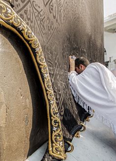 a man is painting the side of a wall with gold and black designs on it