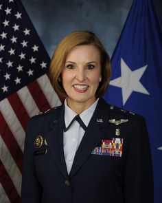 a woman in uniform standing in front of two american flags and an air force officer