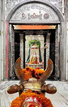 the statue is decorated with orange flowers and gold decorations in front of an ornate doorway