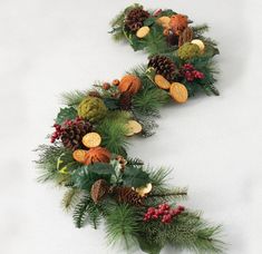 two christmas garlands with pine cones, holly and other holiday decorations on white background