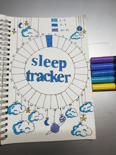 a spiral notebook with the words sleep tracker written on it and colored crayons next to it