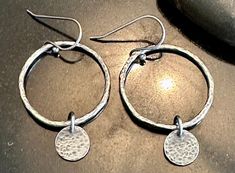 Sterling Silver hoop earrings featuring hand forged and hammered silver discs. These sweet dangles measure approximately 1 3/4" from top of ear wire to the bottom. The little hoops are 1" in diameter and feature 9mm sterling silver discs that swing freely from the hoops. All my hoop earrings come with clear earring backs should you want to use them.    ~~ All jewelry from The Black Lotus Jewelry Co. will arrive securely packaged in a gift box with a lovely ribbon. Perfect for gift giving or a wo Artisan Hammered Round Hoop Earrings, Artisan Silver Hammered Hoop Earrings, Silver Hammered Artisan Hoop Earrings, Artisan Hammered Dangle Hoop Earrings, Sterling Silver Soldered Hoop Earrings, Silver Dangle Hoop Earrings Hand Forged, Silver Hand Forged Dangle Hoop Earrings, Hammered Sterling Silver Hoop Earrings, Hammered Dangle Hoop Earrings