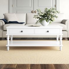 a living room with a white couch, coffee table and mirror on the wall above it