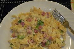 a white plate topped with macaroni and cheese next to a knife and fork