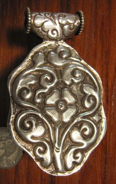 This Tibetian Silver Pendant has a wonderful Orange Coral center dome cab with reddish Amber spots and small turquoise inlay on bezel. The front and back has a wonderfully carved silver floral design. It is 2 7/8 inch long with bezel. 1 3/4 inch wide at face and about 5/8 inch deep. This can be worn on a chain or incorporated into a beaded necklace. Ornate Antique Silver Carved Jewelry, Carved Silver Medallion Jewelry, Traditional Carved Silver Jewelry, Ornate Carved Medallion Jewelry, Traditional Polished Medallion Jewelry, Traditional Medallion Jewelry With Polished Finish, Traditional Carved Medallion Jewelry, Orange Coral, Resin Beads