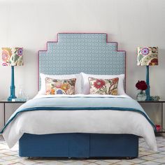 a bed with two lamps on either side and a blue headboard in the middle