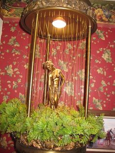 a golden statue sitting on top of a planter in front of a red wall