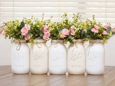 four mason jars with flowers in them sitting on a table