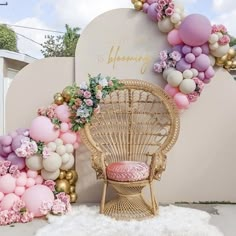 a wicker chair sitting in front of a wall with balloons and flowers on it