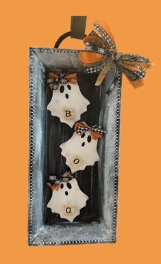 three halloween decorations in a frame on an orange background with the word boo spelled out