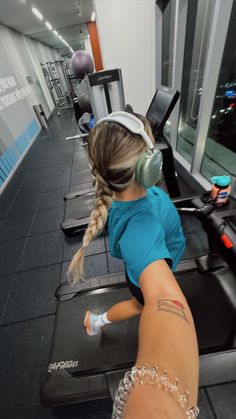 a woman with headphones is running on a treadmill