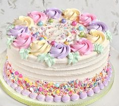 a multi layer cake with frosting and sprinkles on the top is decorated in pastel colors