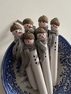 four snowmen on toothbrushes in a blue and white plate