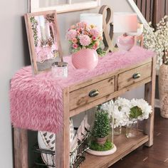 a pink table with flowers and pictures on it in front of a staircase way mirror