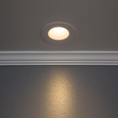 a light that is on above a wall in a room with gray walls and white trim