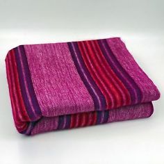 two purple and red striped towels folded on top of each other in front of a white background