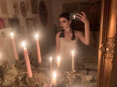 a woman standing in front of a mirror with candles