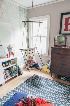 a child's room with a swing, bookshelf and toys on the floor