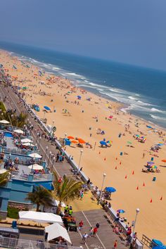 an aerial view of a beach with many people and umbrellas on the shore line