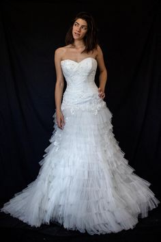 a woman in a white wedding dress posing for a photo with her hands on her hips