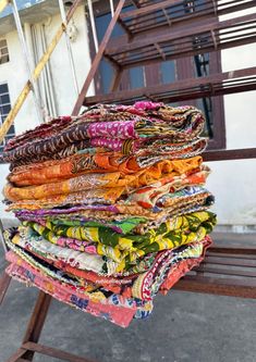 a pile of cloths sitting on top of a wooden bench next to a building