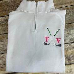 two golf clubs embroidered on the back of a white shirt with pink and green letters