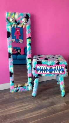 a brightly colored monster themed dressing table and mirror in a pink room with hardwood flooring