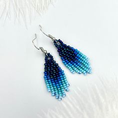 two pairs of beaded earrings with blue beads hanging from them on a white surface