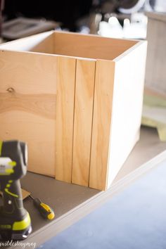 a wooden box sitting on top of a table next to a power drill and screwdriver