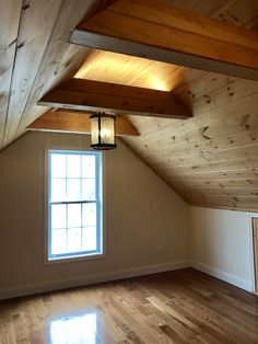 an empty room with wood flooring and a lantern hanging from the ceiling in front of a window